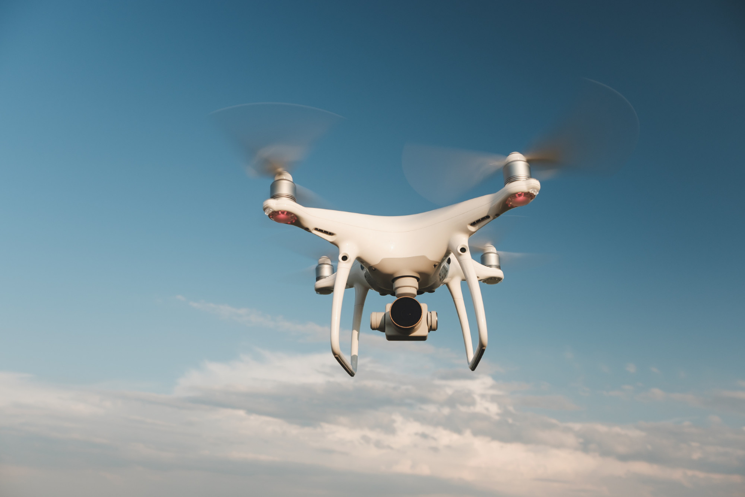 white-drone-hovering-bright-blue-sky